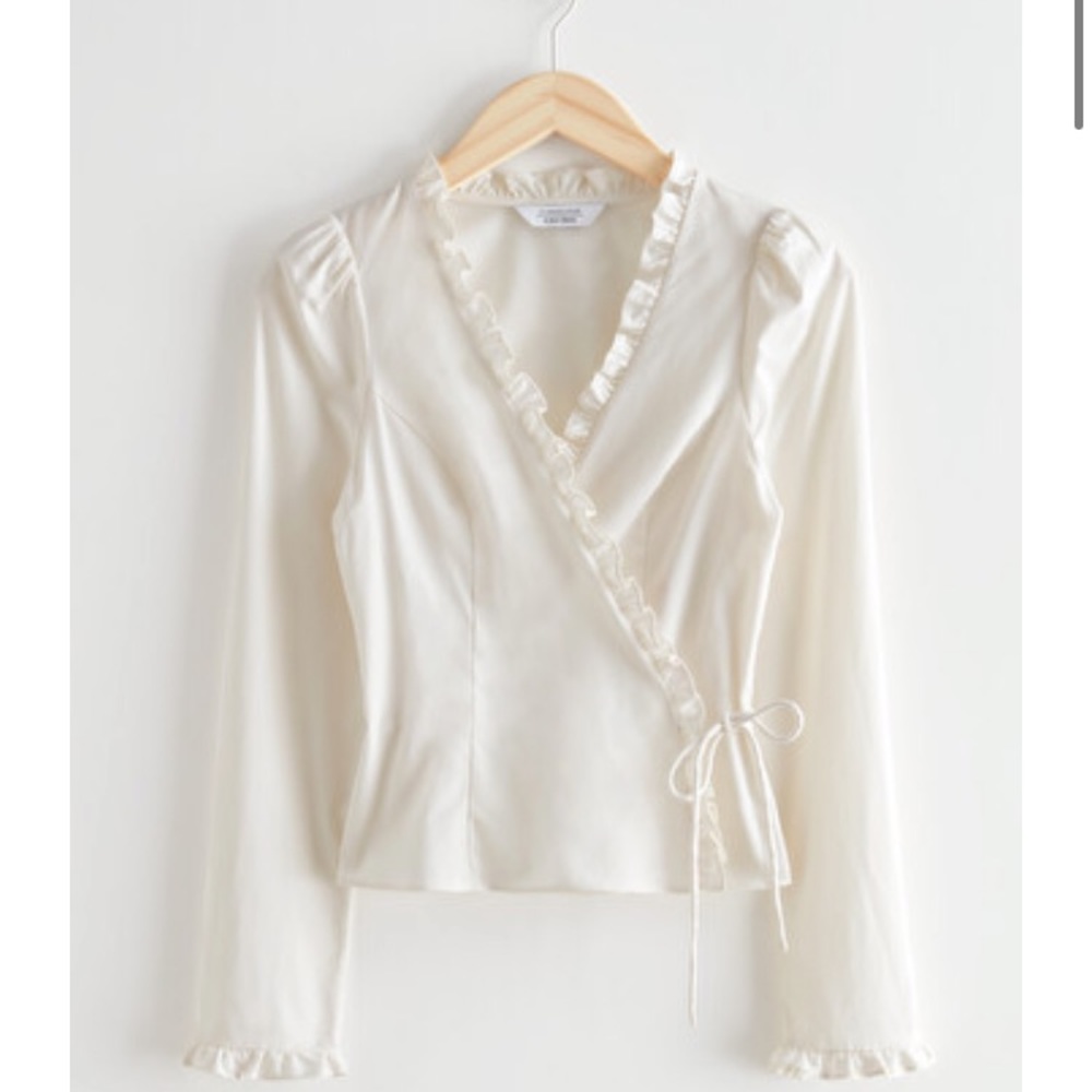 Tailored wrap top w/ accentuated waistline, ruffled detailing & puff shoulders.